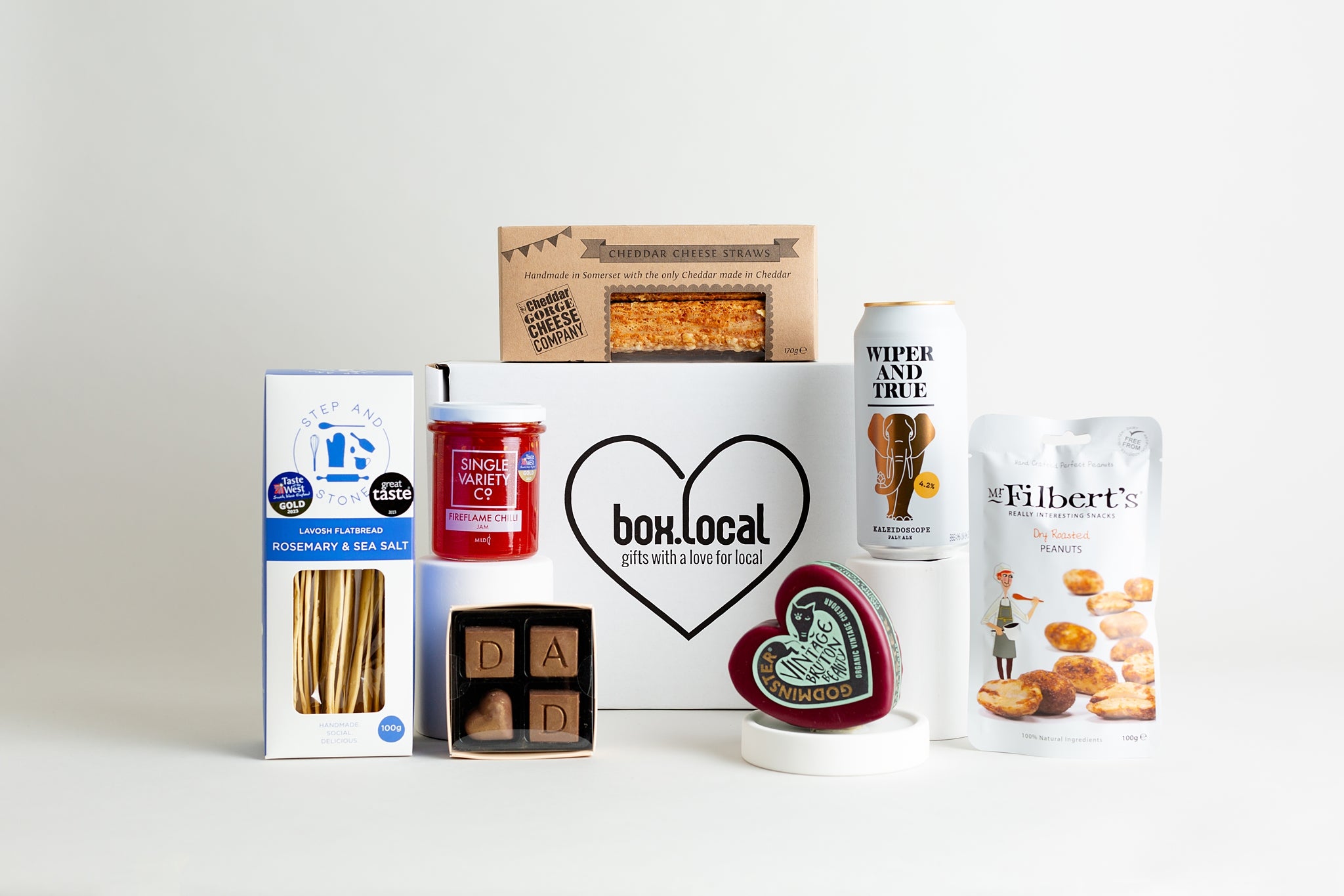This fabulous hamper includes:
The Cheddar Gorge Cheese Co. 5 Cheese Straws
Wiper & True Kaleidoscope Pale Ale Beer 440ml Can
Mr FIlbert's Dry Roasted Peanuts 100g
Godminster Vintage Organic Cheddar Truckle 200g
Ooh! Chocolata Hand-Dipped Ginger Batons 175g
Single Variety Co. Fireflame Chilli Jam 225g
Step and Stone Lavosh Flatbread Rosemary and Sea Salt 100g